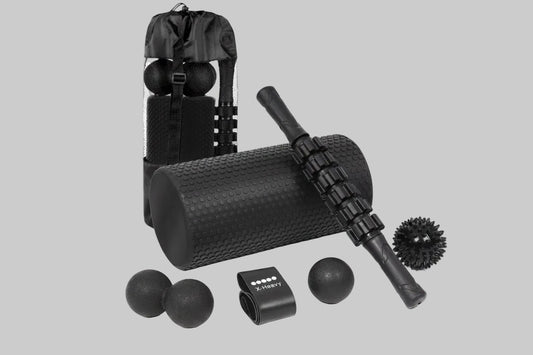 Collection of black massage tools including a foam roller, massage ball, and roller stick on a white background.